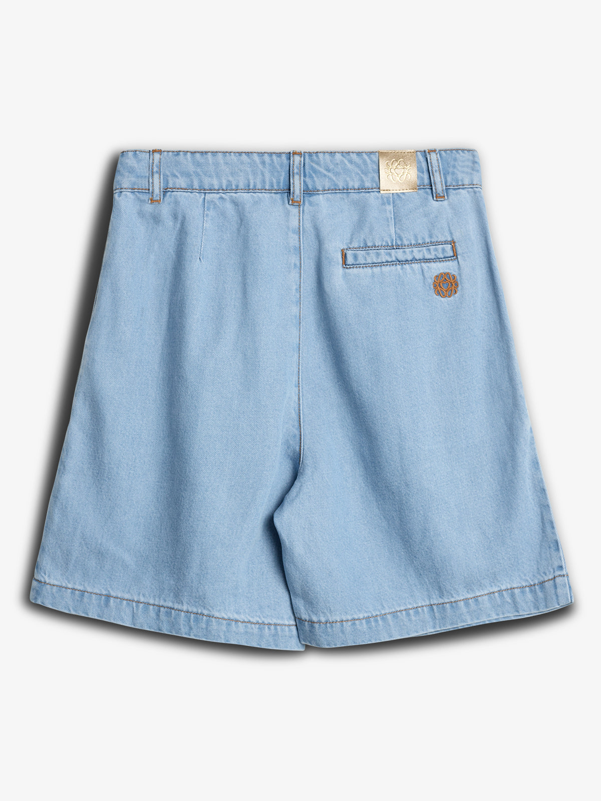 Light blue denim shorts are laid flat, featuring belt loops and a single back pocket with a brown embroidered logo. A beige logo label is attached near the waistband.