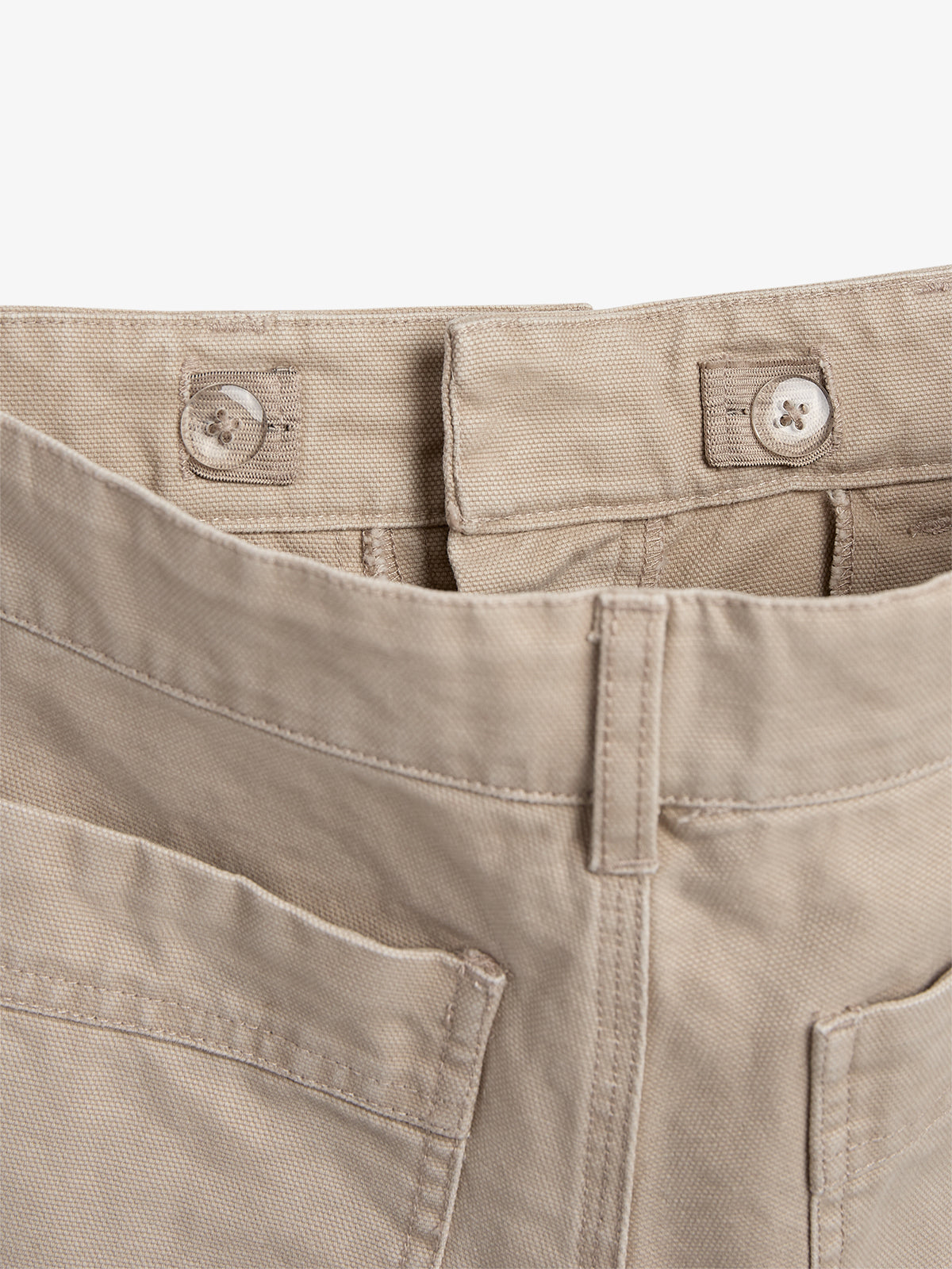 A pair of beige pants with a close-up view of the top buttons and belt loops, set against a plain, white background.