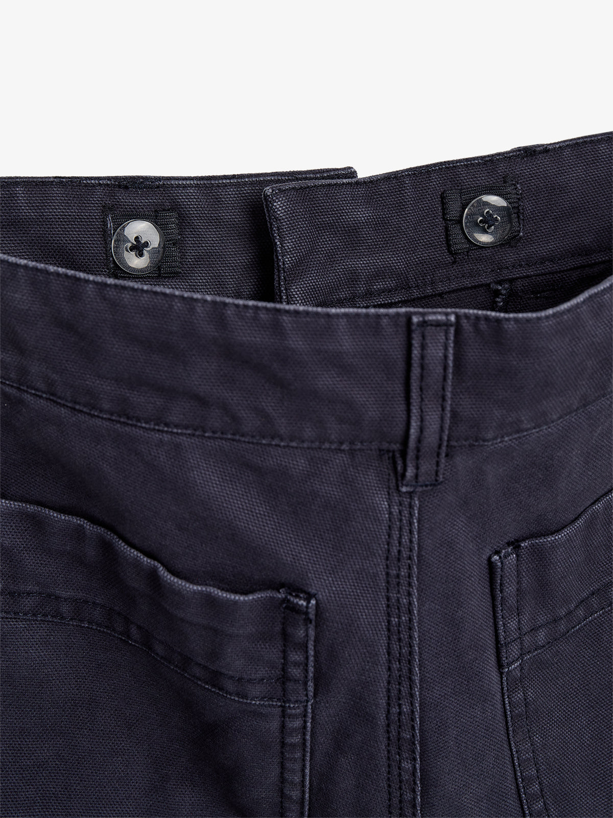 Dark blue fabric pants with visible front pockets and button closures, laid flat against a white background, showcasing detailed stitching and texture.