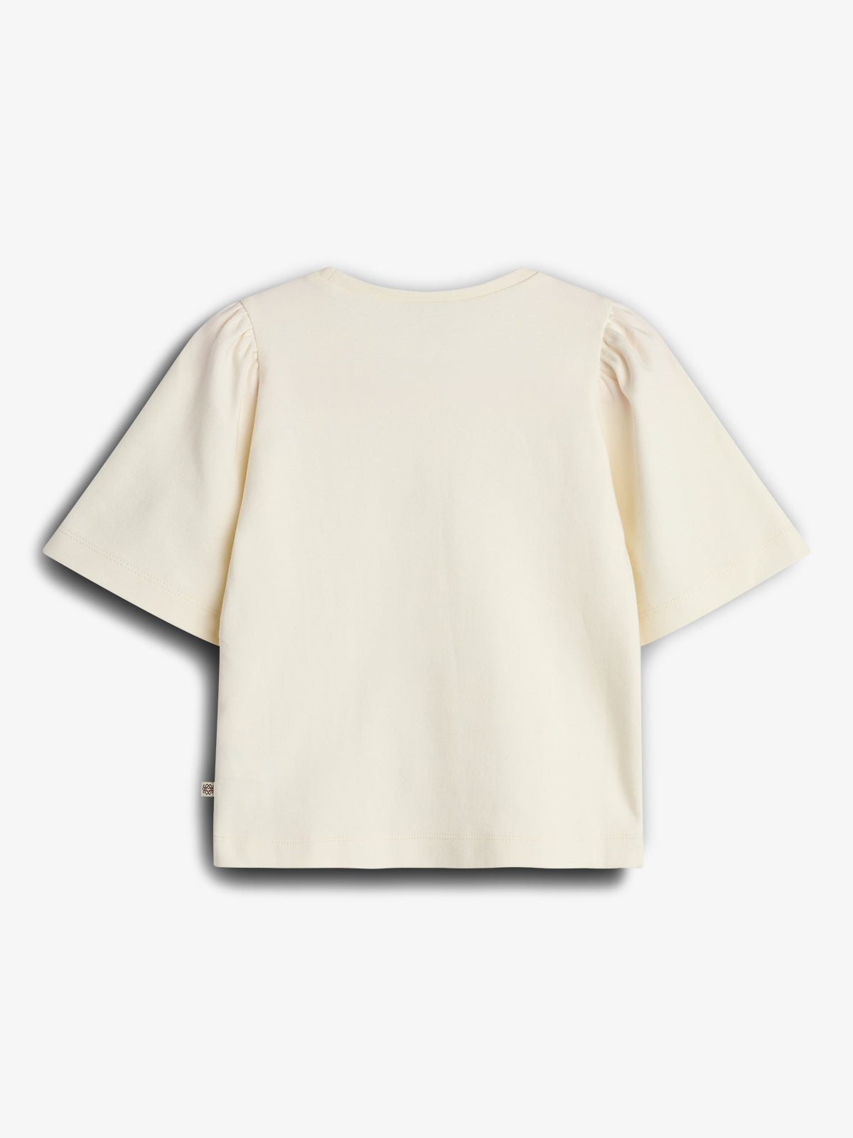 A cream-colored, short-sleeve t-shirt with slight puffed detailing at the shoulders is laid flat. It is set against a plain white background, emphasizing its simple, elegant design.