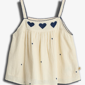 Cream-colored tank top adorned with dark blue heart embroidery and scalloped trim, hanging flat against a plain white background.